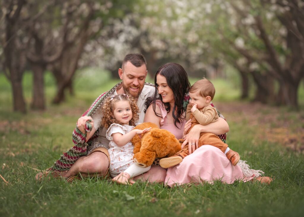 Melbourne family sitting with 2 toddlers wrapped in blanket during an outdoor spring family session